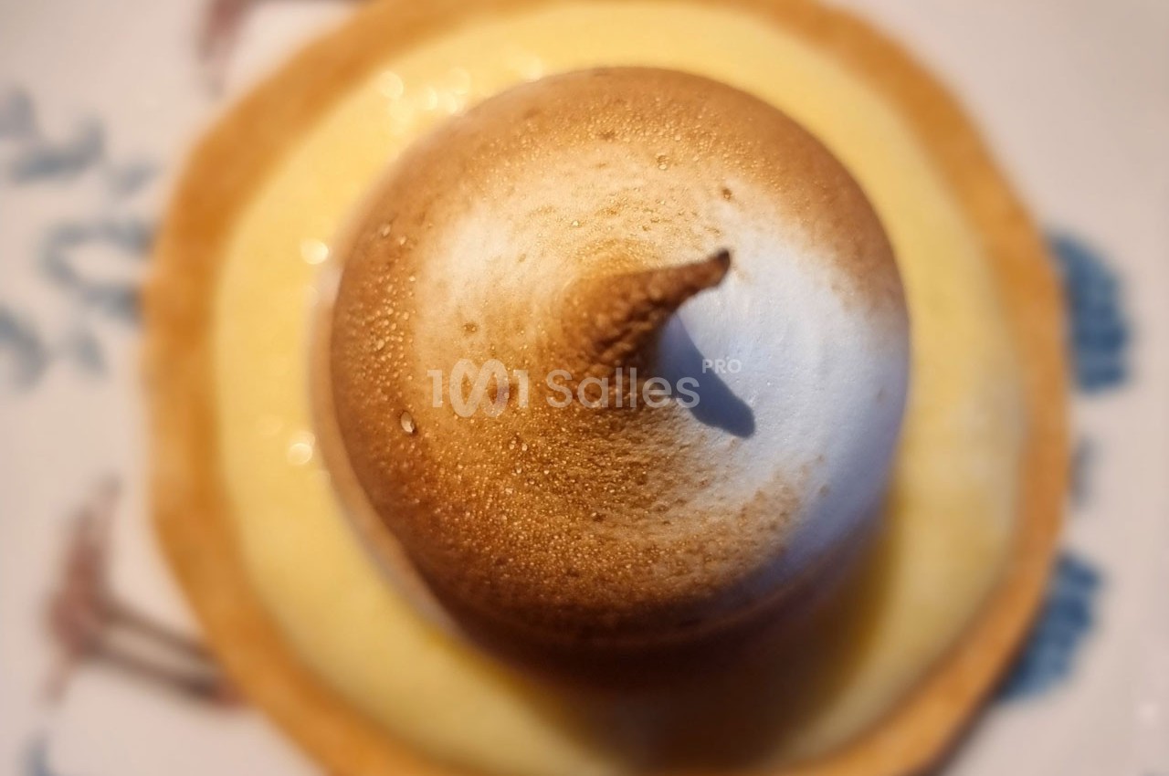 Tartelette au citron surmontée d'une meringue dorée, vue de dessus avec un léger flou en arrière-plan.
