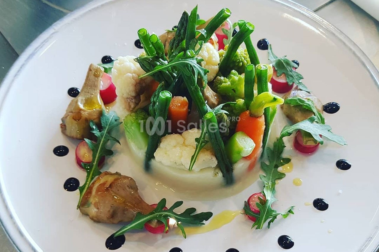 Assiette de légumes variés joliment dressés avec des touches de sauce et des décorations de roquette.