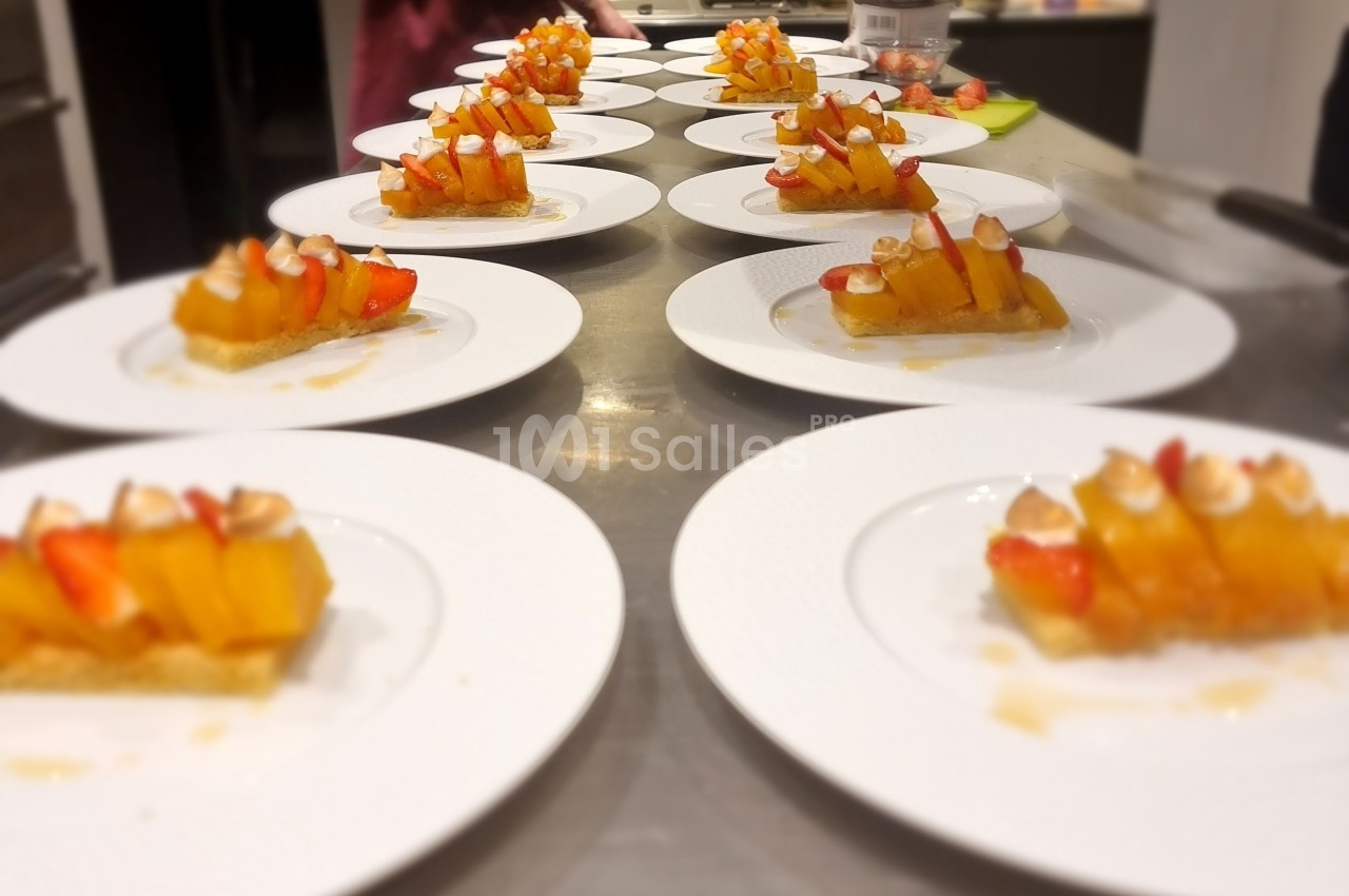 Assiettes alignées contenant des desserts composés de fruits frais et de biscuits, disposées sur un plan de travail.