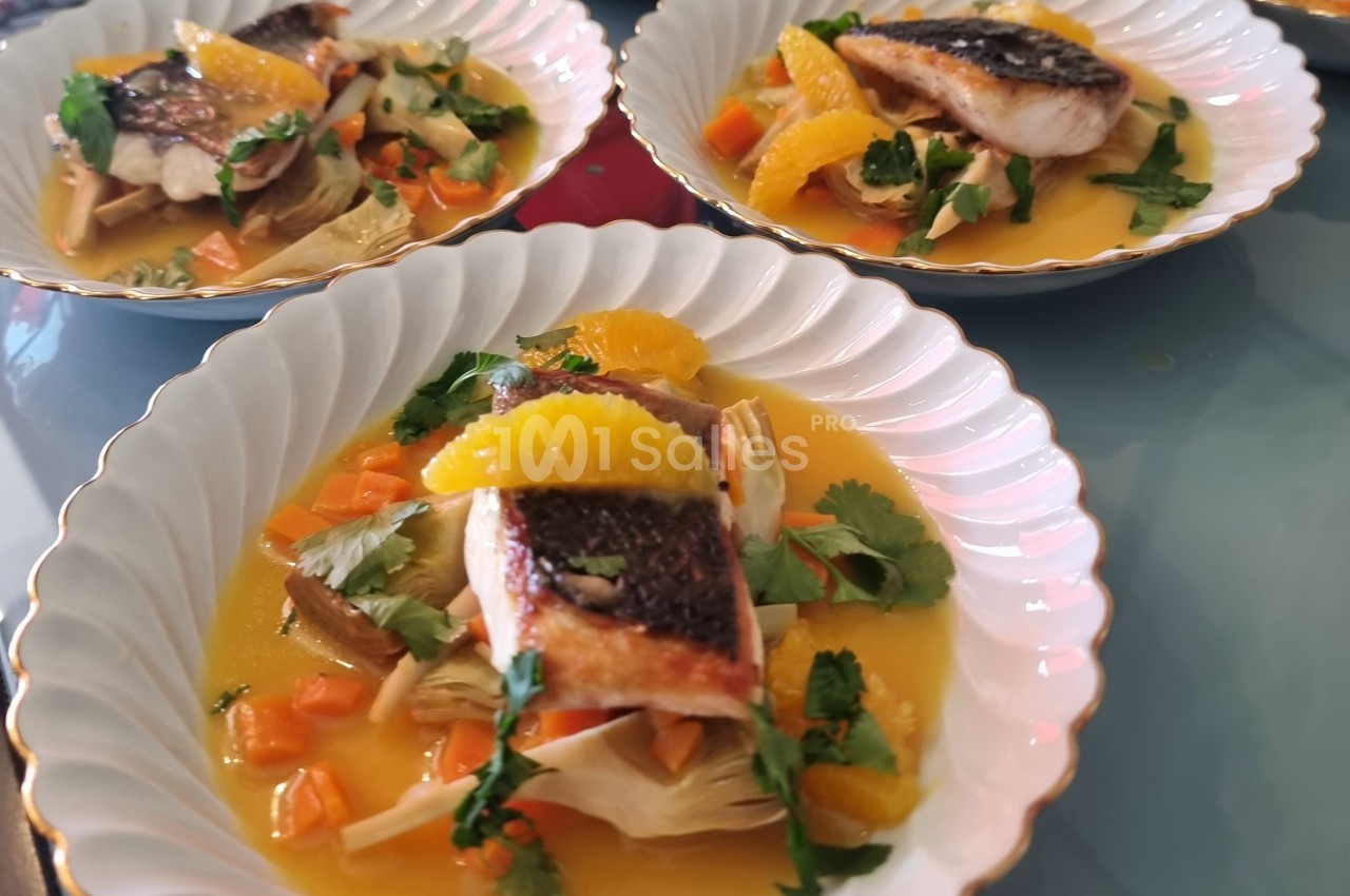 Filets de poisson grillés servis avec des légumes, des quartiers d'orange et une sauce, présentés dans des assiettes…