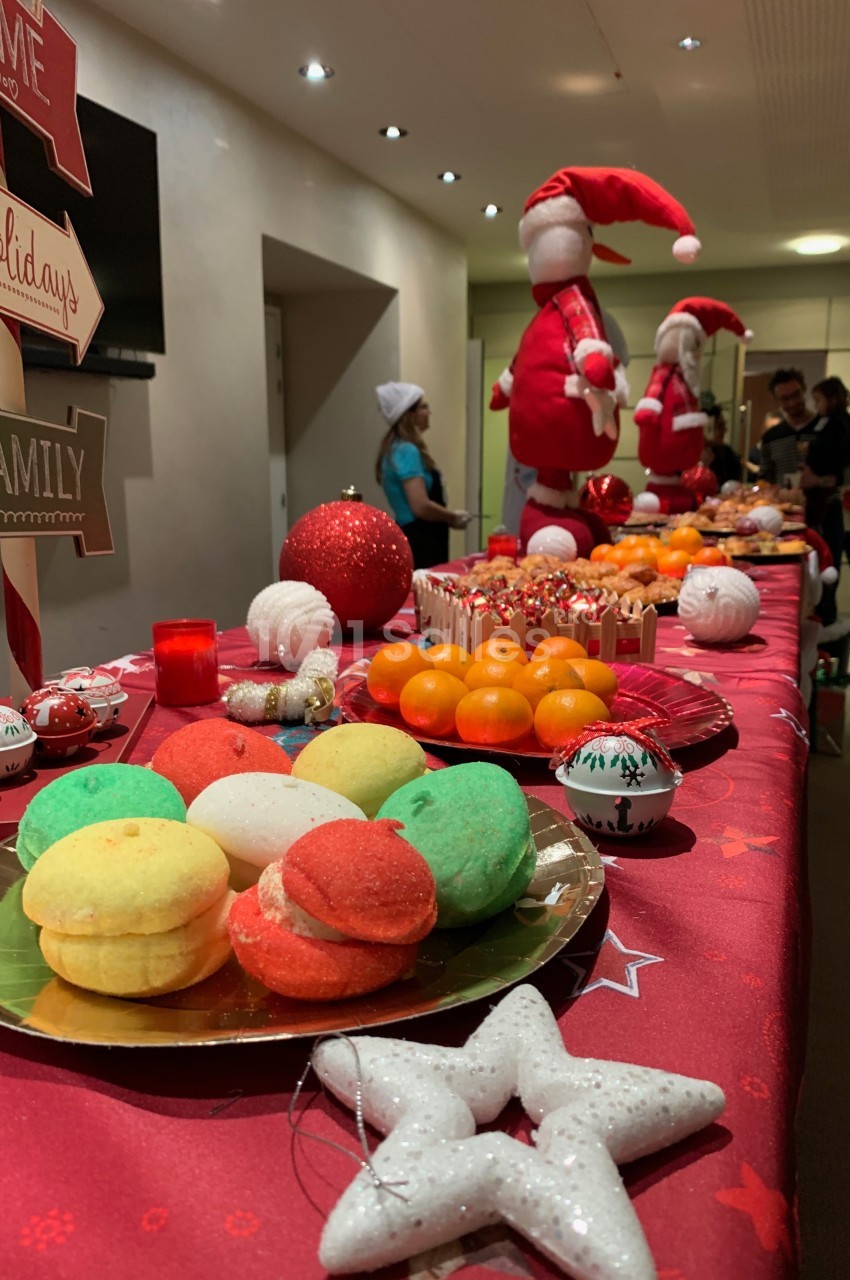 Table décorée sur le thème de Noël avec des pâtisseries colorées, des fruits et des décorations festives.