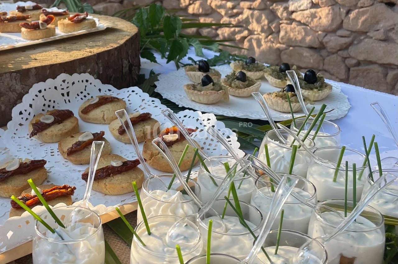 Plateau de verrines et amuse-bouches variés disposés sur une table décorée de feuilles et de napperons.