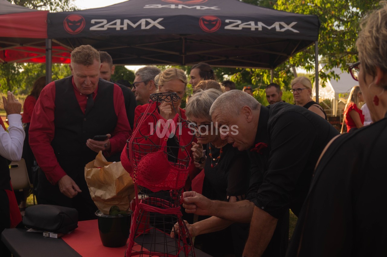 Des personnes observent un mannequin métallique décoré d'un soutien-gorge rouge lors d'un événement en plein air.