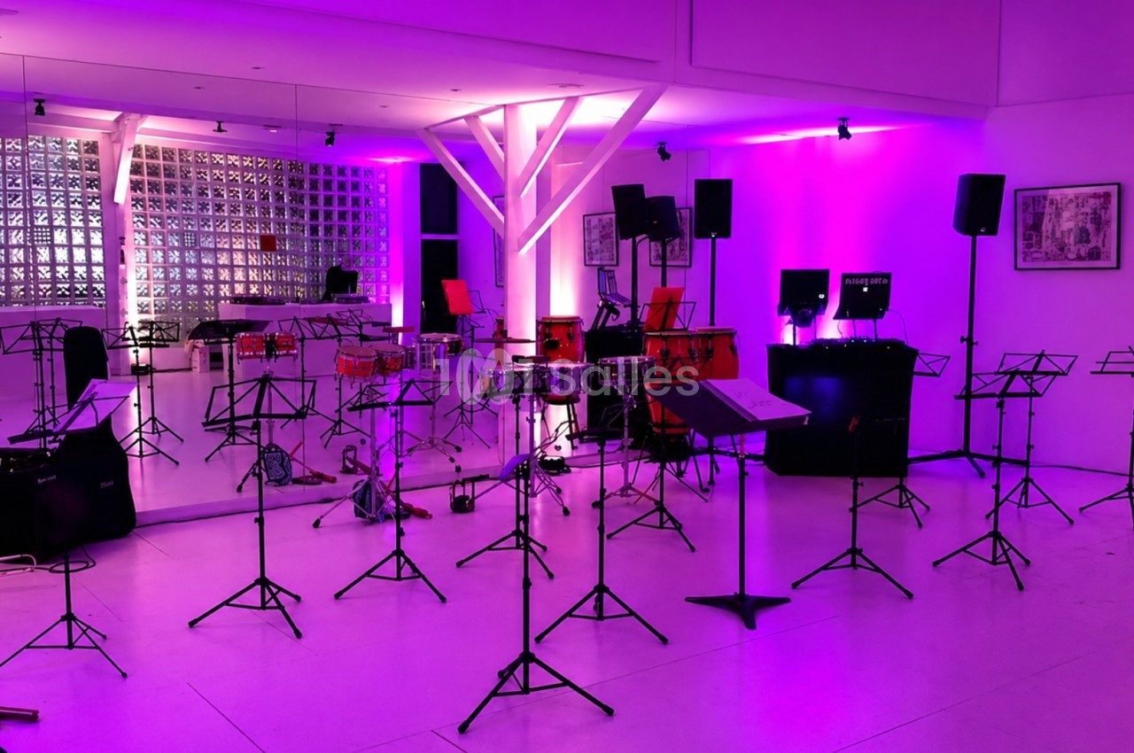 Salle de répétition avec pupitres vides, instruments de musique et éclairage violet.