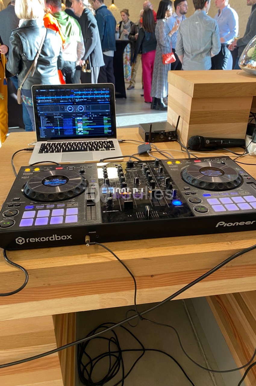 Table de mixage Pioneer DJ avec ordinateur portable ouvert, installée sur un comptoir en bois lors d'un événement.