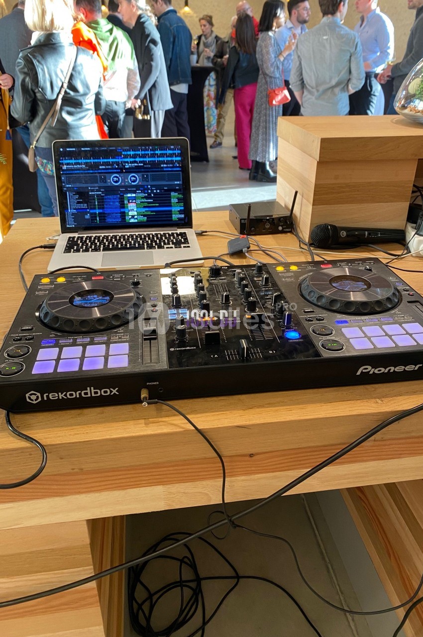 Table de mixage Pioneer DJ avec ordinateur portable ouvert, installée sur un comptoir en bois lors d'un événement.
