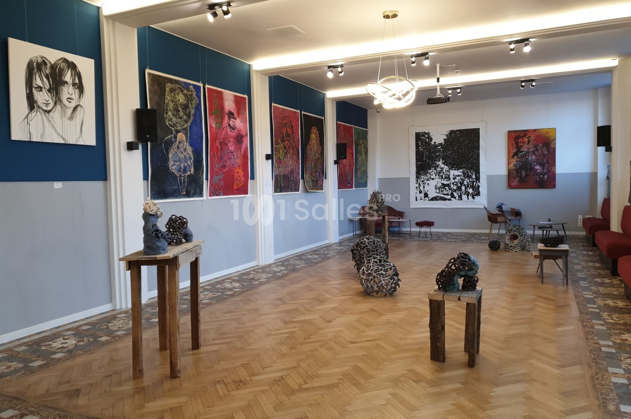 Salle d'exposition avec des œuvres d'art contemporain accrochées aux murs et des sculptures disposées au sol et sur des…
