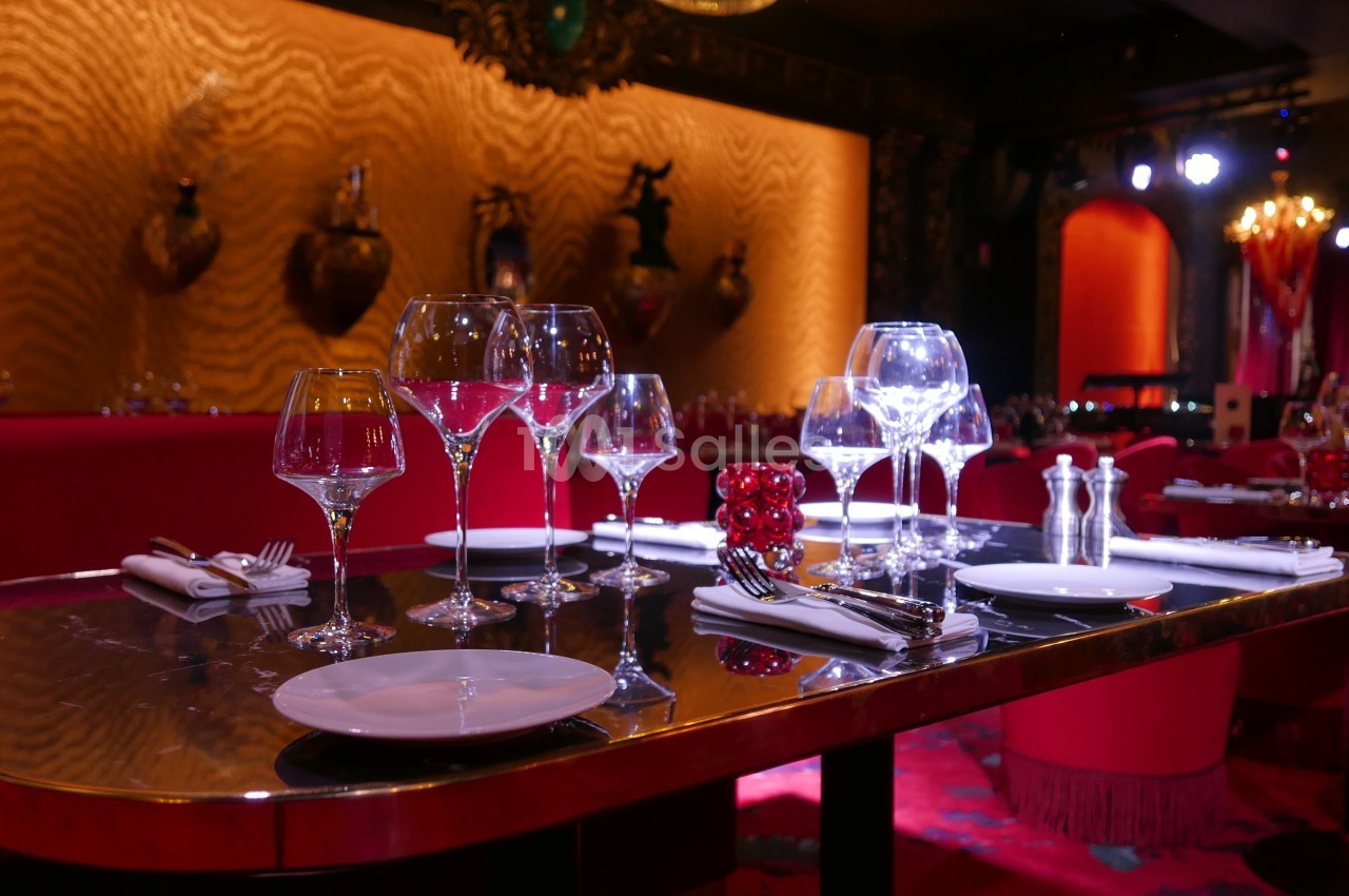 Table élégamment dressée avec verres, assiettes et couverts, dans un restaurant à l'ambiance tamisée et chaleureuse.
