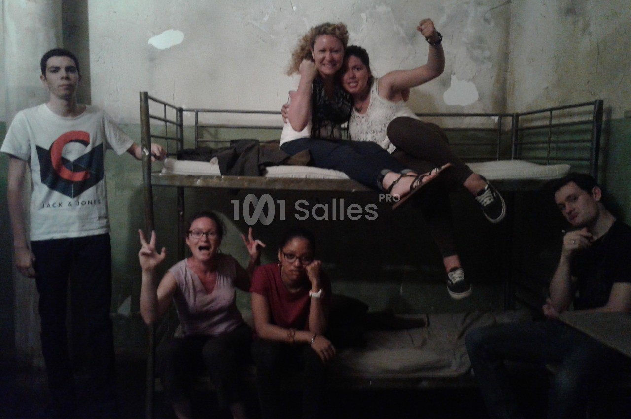 Un groupe de personnes pose dans une pièce avec des lits superposés et un mur à l'aspect vieilli.