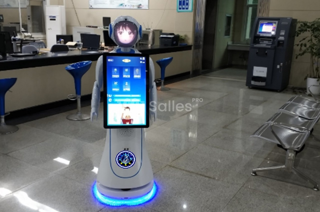 Robot interactif avec écran tactile dans un hall moderne, près de sièges et d'un distributeur automatique.