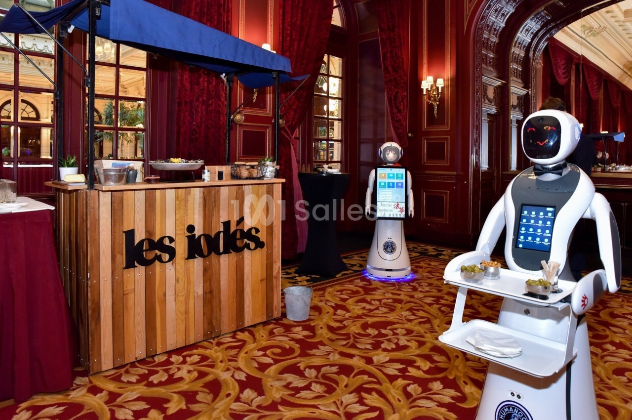 Un robot serveur avec des plateaux de nourriture dans un espace élégant avec stand en bois et décorations rouges.