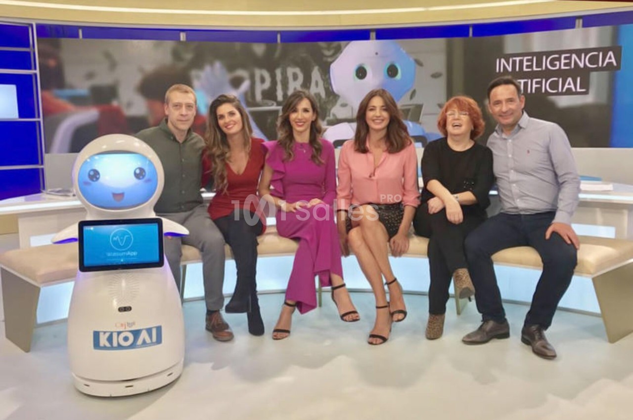 Un groupe de personnes assises sur un canapé avec un robot interactif dans un studio télévisé.