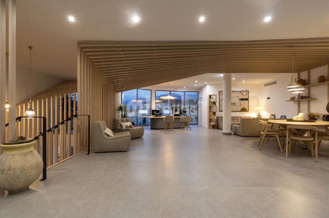 Espace intérieur moderne avec un salon ouvert, des meubles en bois clair et un éclairage chaleureux.