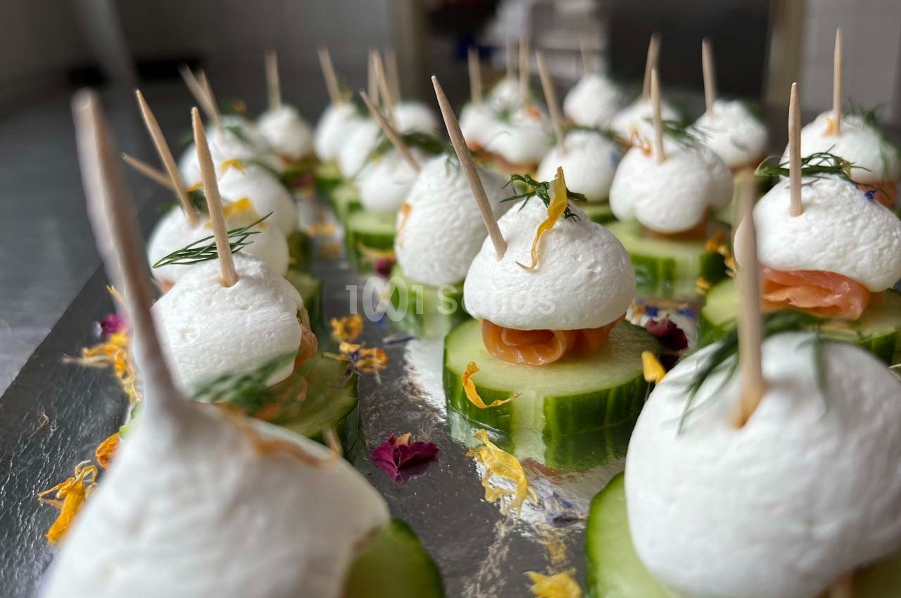 Bouchées apéritives sur rondelles de concombre, garnies de saumon, fromage frais et herbes, fixées par des piques.