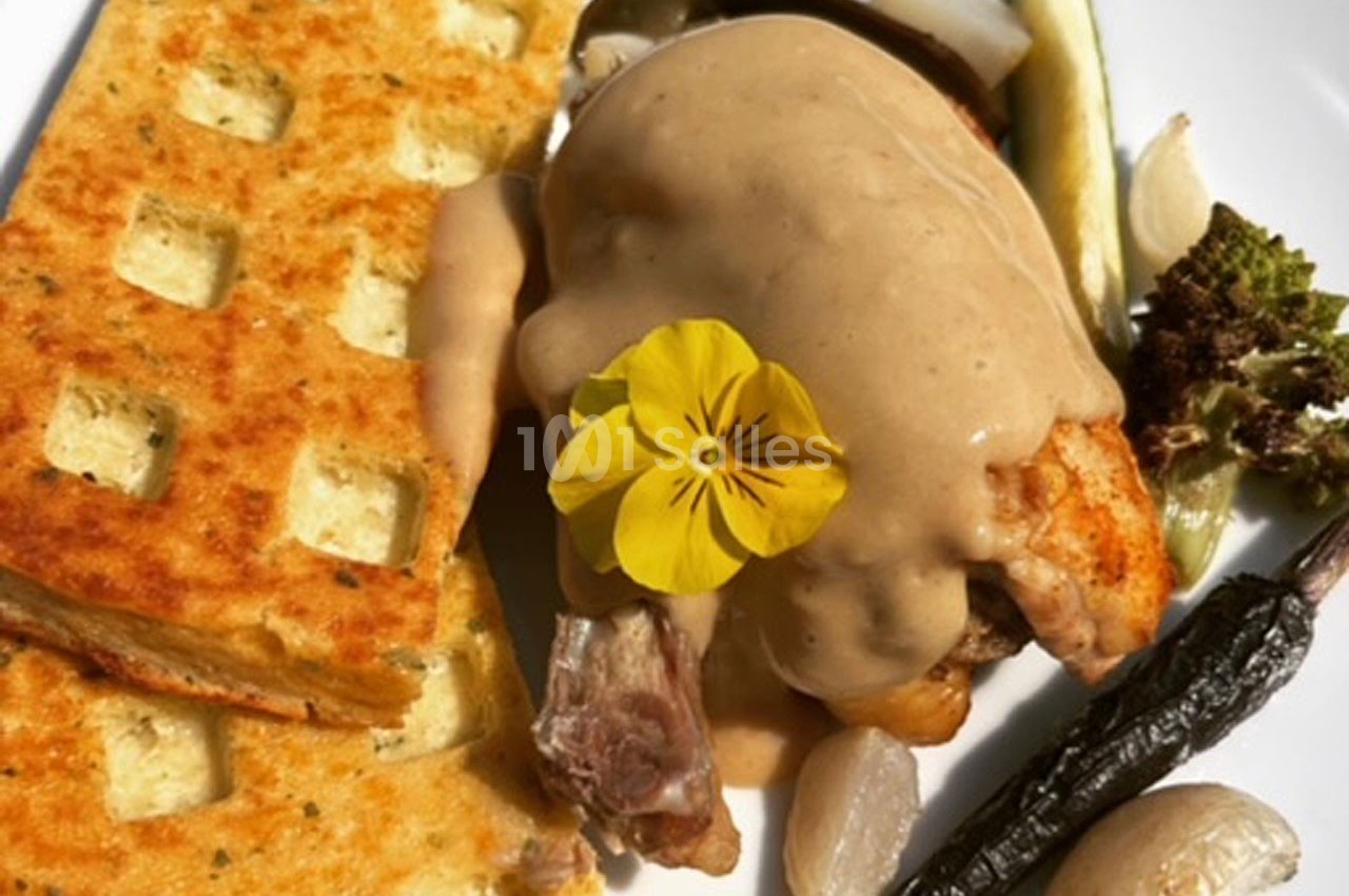 Assiette composée d'une viande en sauce, légumes variés, gaufre salée et fleur comestible en décoration.