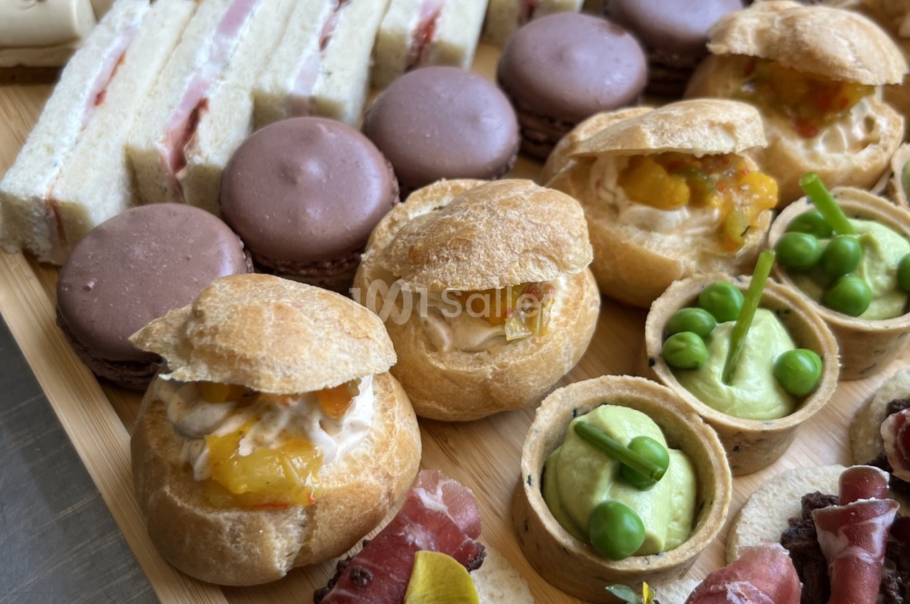 Plateau de bouchées variées comprenant choux garnis, macarons, sandwichs et tartelettes salées.