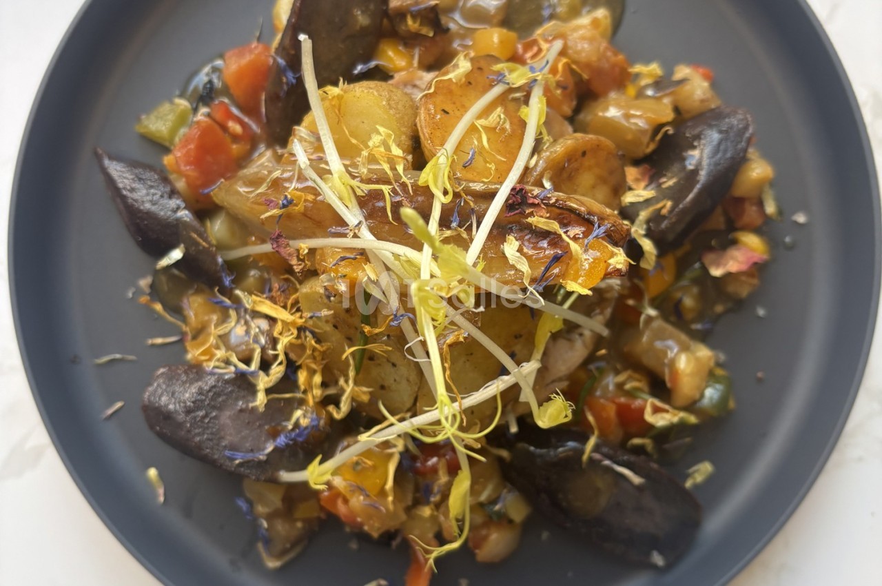 Assiette de légumes rôtis avec pommes de terre violettes, garnie de pousses fraîches et de fleurs comestibles.