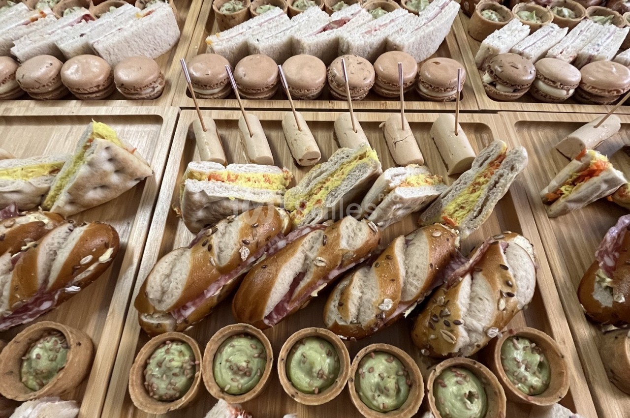 Plateaux en bois garnis de sandwichs variés, macarons, roulés et petites coupelles de guacamole.