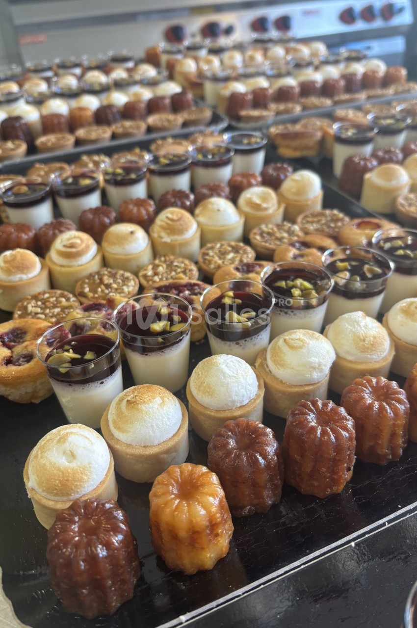 Plateau de desserts variés comprenant cannelés, verrines, tartelettes et autres pâtisseries miniatures.
