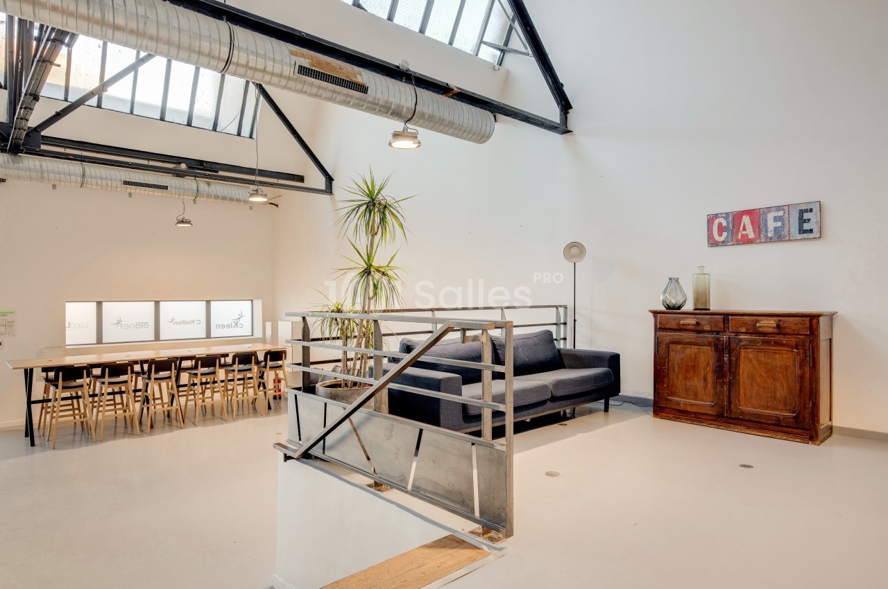 Espace intérieur lumineux avec un canapé, une table longue, des chaises, une armoire en bois et une décoration ’CAFE’.