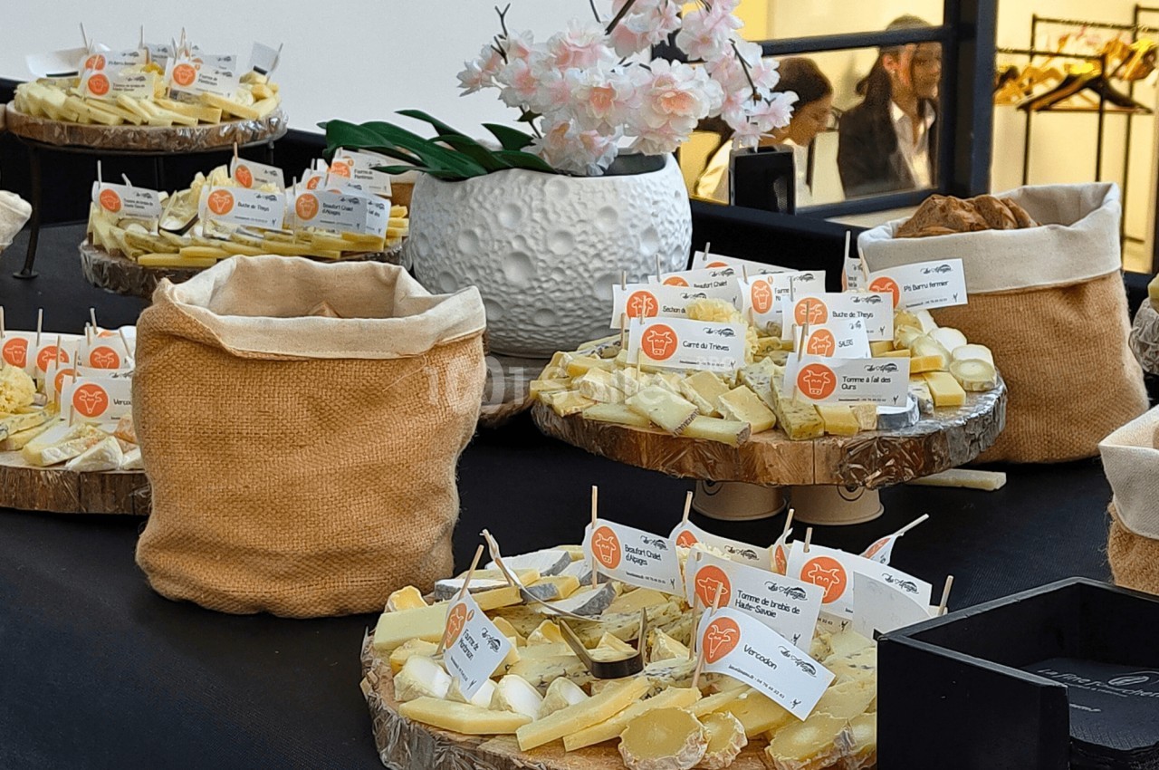 Plateaux de fromages variés présentés sur une table avec des étiquettes descriptives et une décoration florale.