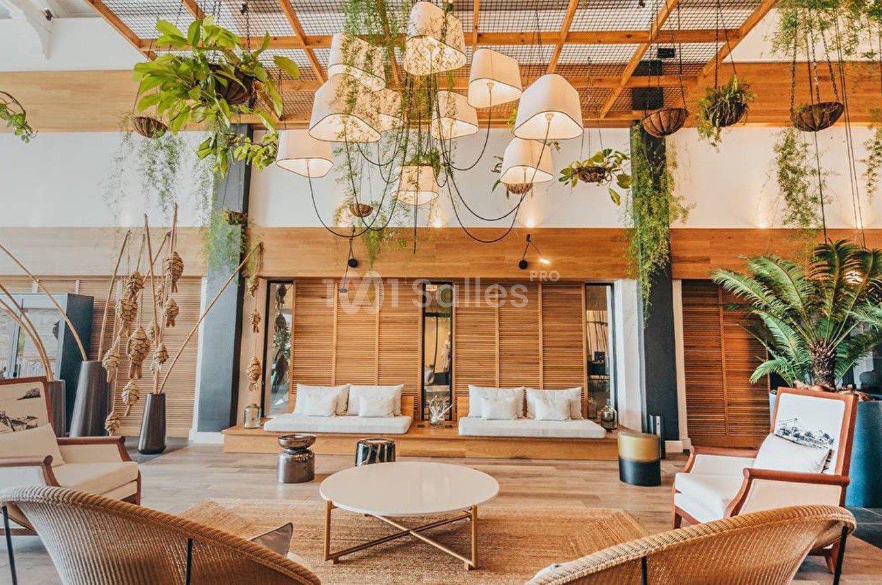 Espace lounge lumineux avec mobilier en rotin, plantes suspendues et décoration naturelle dans un cadre chaleureux.
