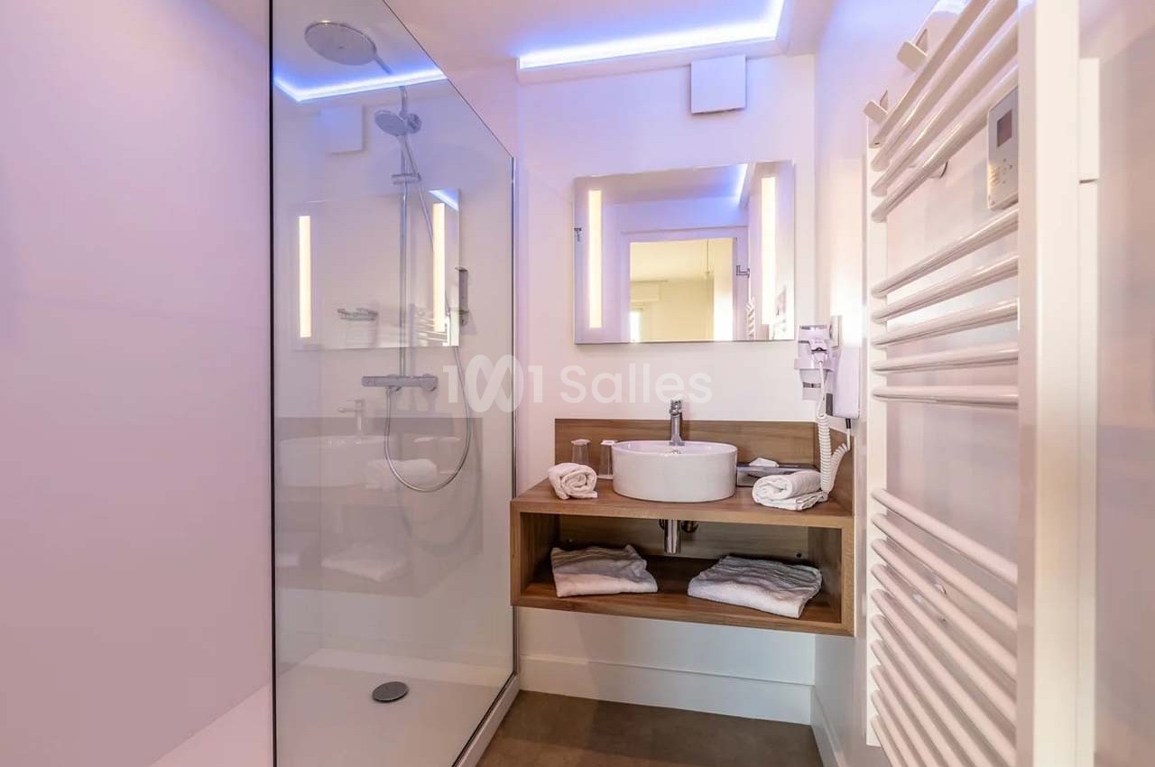 Salle de bain moderne avec douche à l'italienne, vasque sur meuble en bois, miroir éclairé et sèche-serviettes.