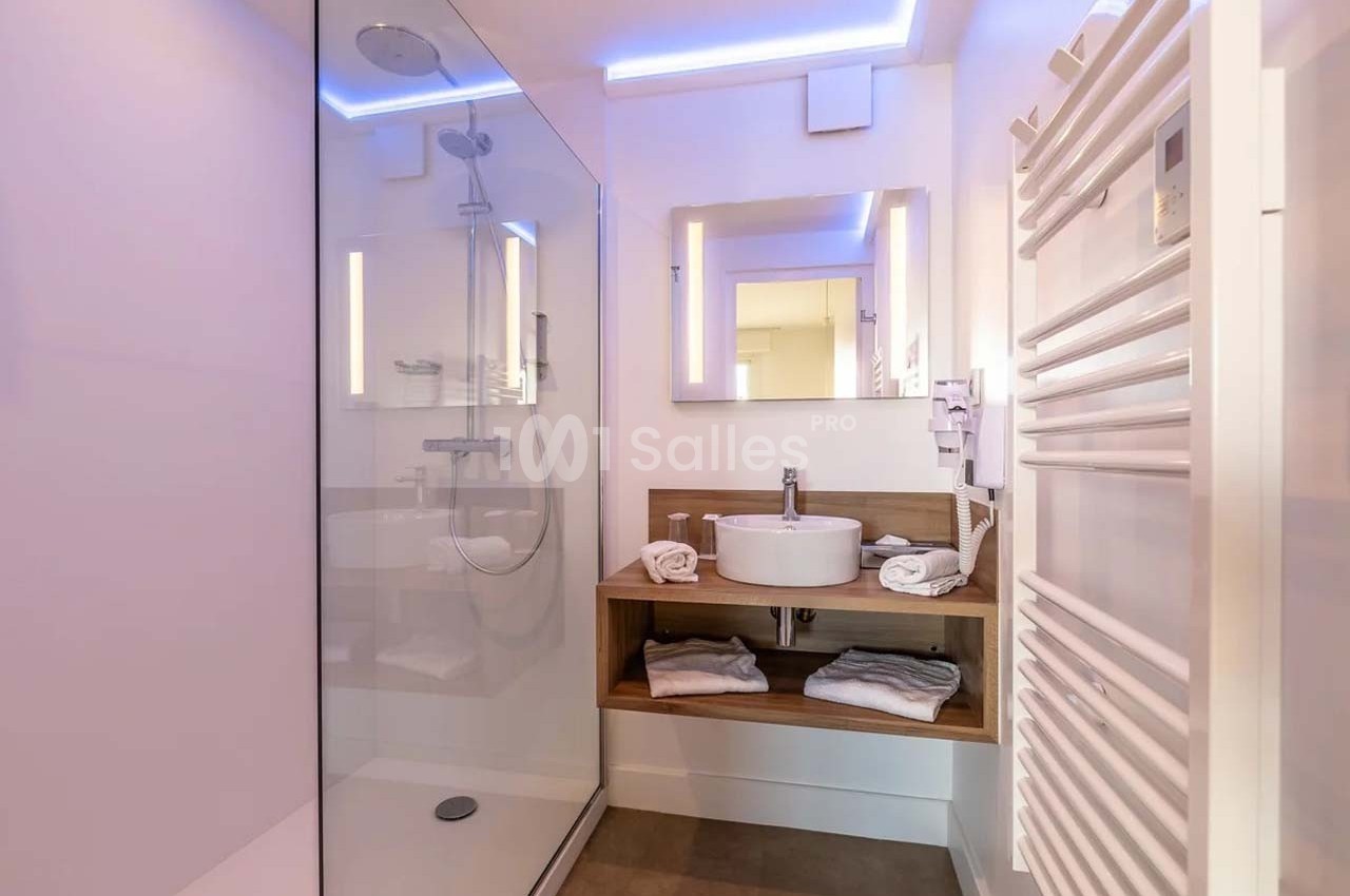 Salle de bain moderne avec douche à l'italienne, vasque sur meuble en bois, miroir éclairé et sèche-serviettes.