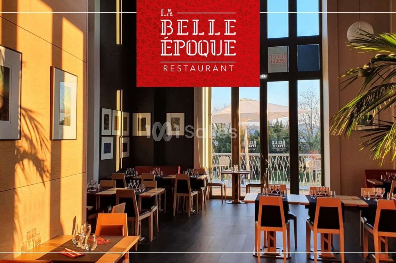 Salle de restaurant lumineuse avec tables dressées, grandes baies vitrées et décorations murales modernes.