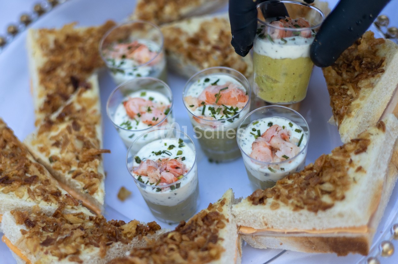 Assortiment de verrines aux crevettes et toasts garnis d'oignons frits disposés sur un plateau.