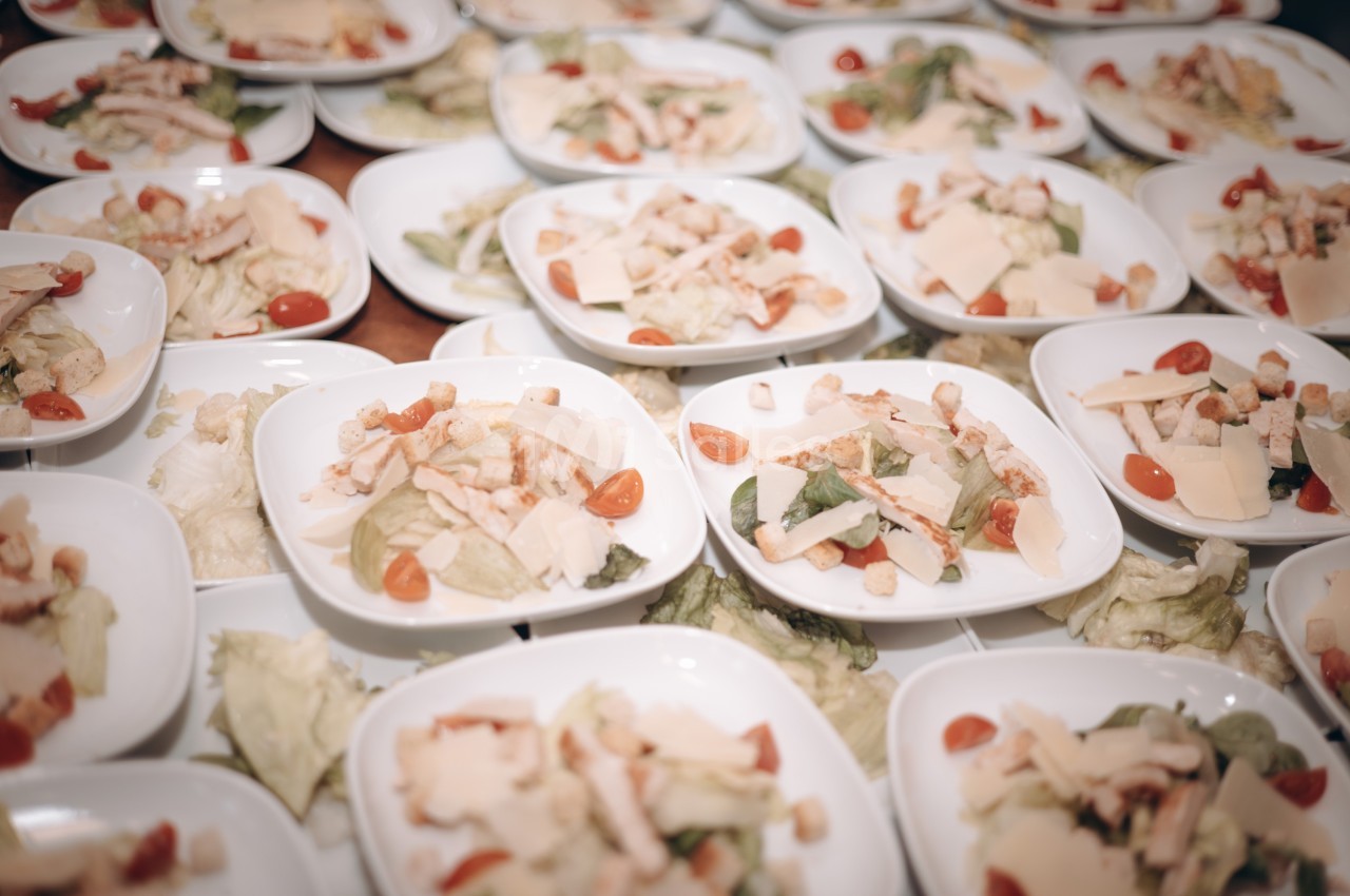 Assiettes de salade composées de laitue, tomates cerises, croûtons, fromage et morceaux de poulet.