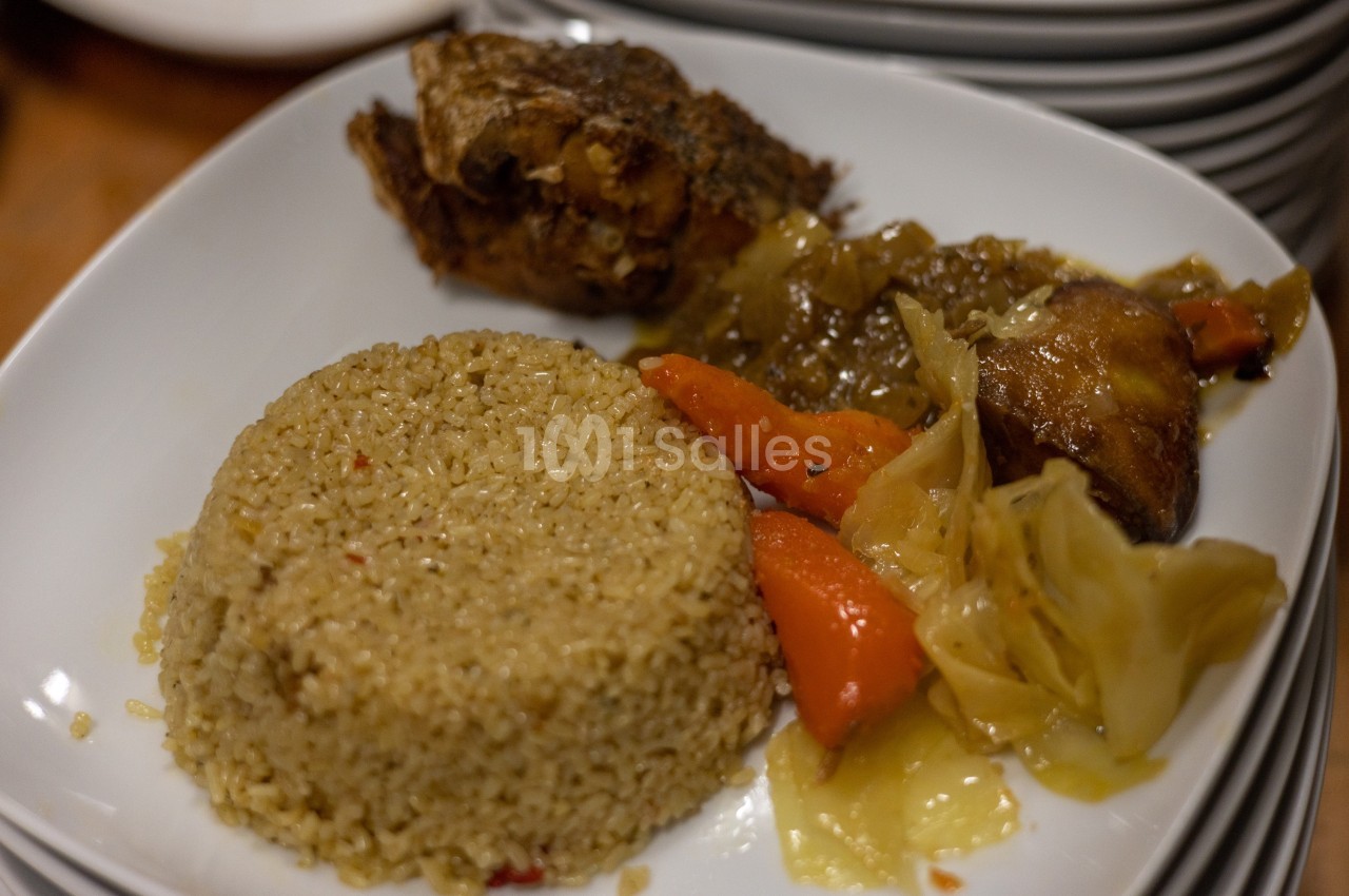 Assiette contenant du riz, des légumes braisés et un morceau de viande, servie sur une table.