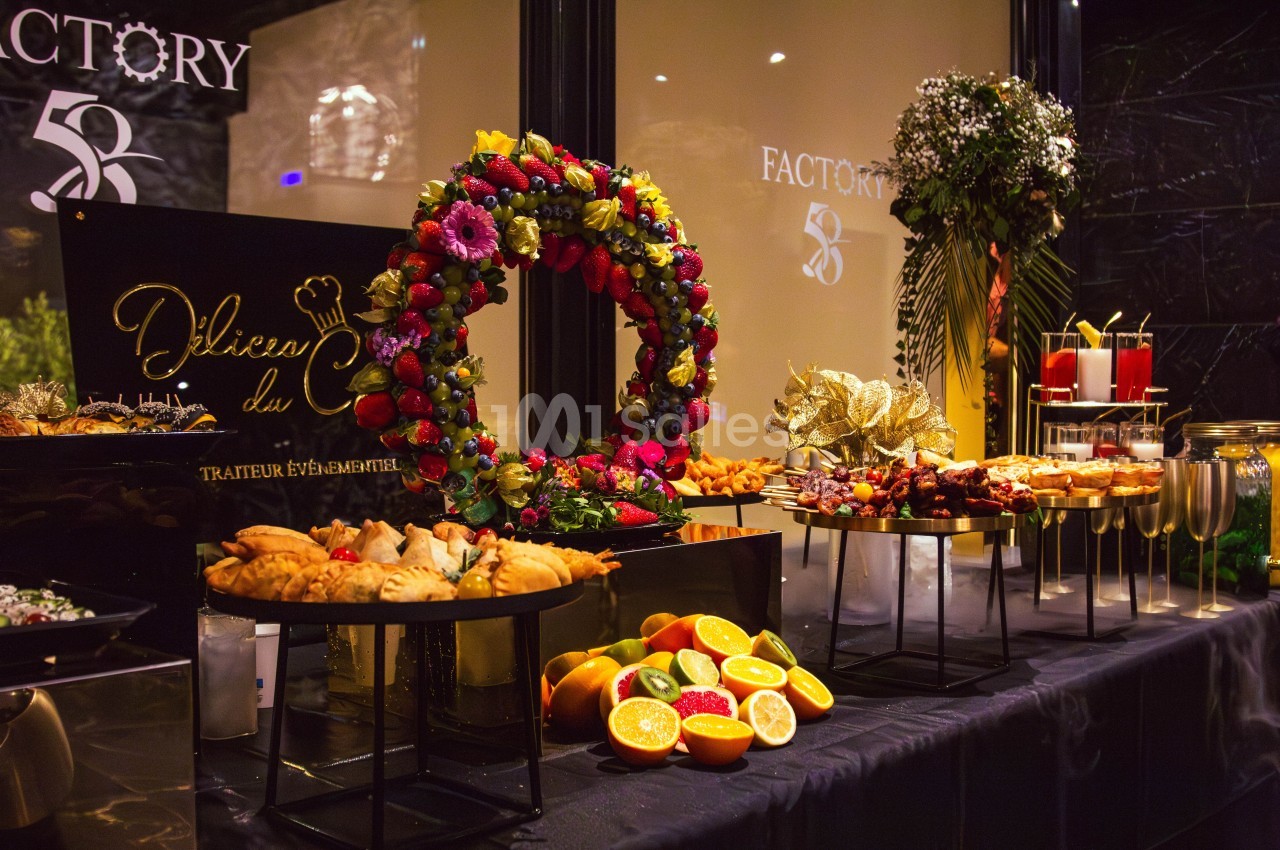 Buffet décoratif avec assortiment de fruits, pâtisseries, verrines et décorations florales sur une table élégante.