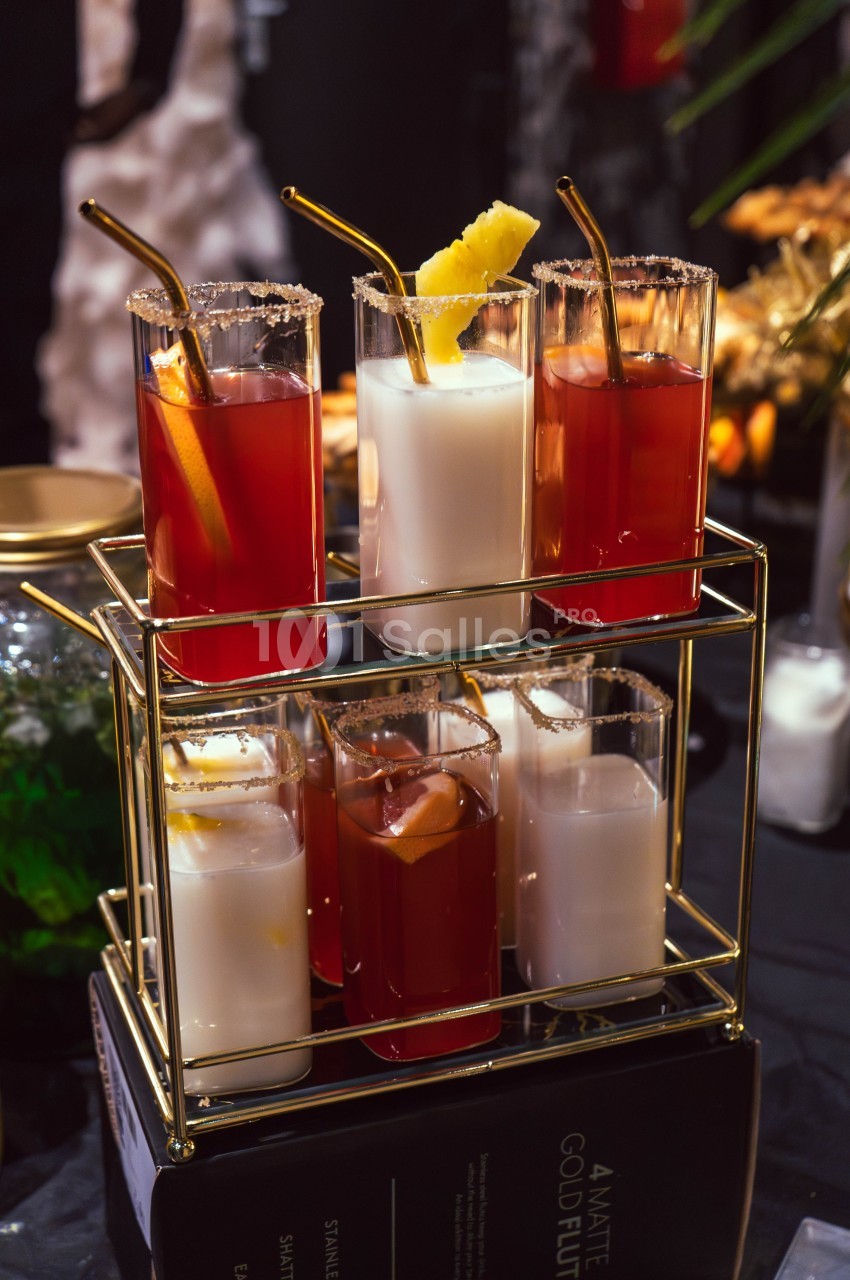 Six cocktails variés, rouges et blancs, servis dans des verres avec pailles dorées sur un présentoir à deux niveaux.