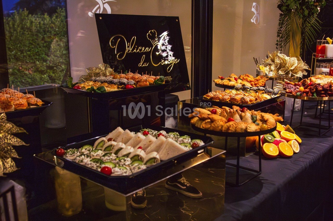 Buffet varié avec sandwiches, fruits, viennoiseries et plats salés, présenté sur des plateaux décoratifs.