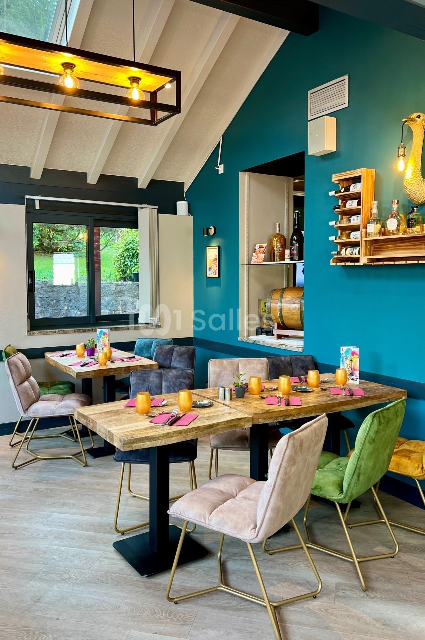 Salle de restaurant lumineuse avec tables en bois, chaises colorées et décoration murale moderne.