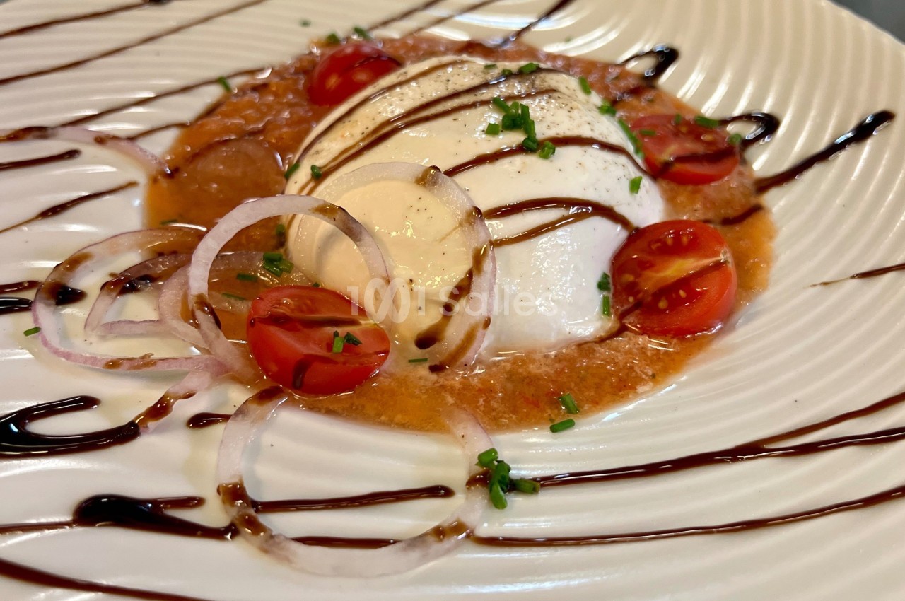 Assiette de burrata garnie de tomates cerises, rondelles d'oignon, ciboulette et filet de vinaigre balsamique.