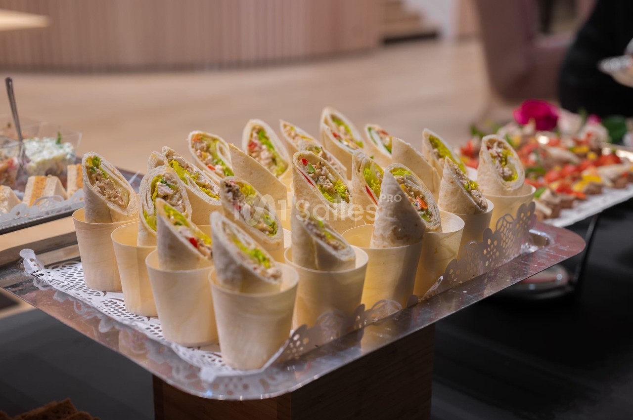 Assortiment de wraps garnis présentés dans des cônes en bois sur un plateau décoré.