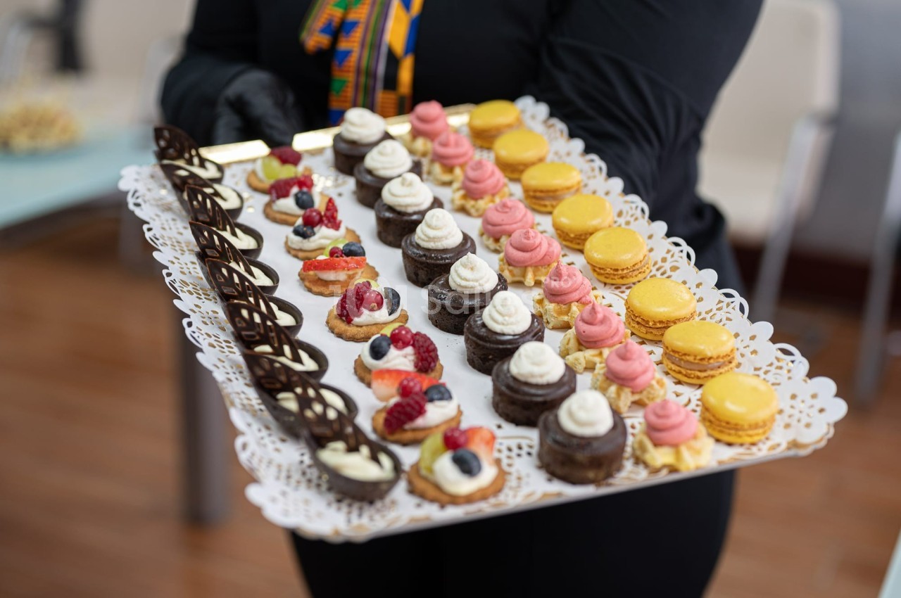 Plateau de mignardises variées comprenant macarons, mini-gâteaux au chocolat et desserts garnis de fruits rouges.