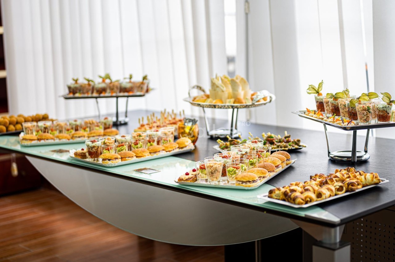 Buffet de verrines et amuse-bouches variés disposés sur une table dans un cadre lumineux.