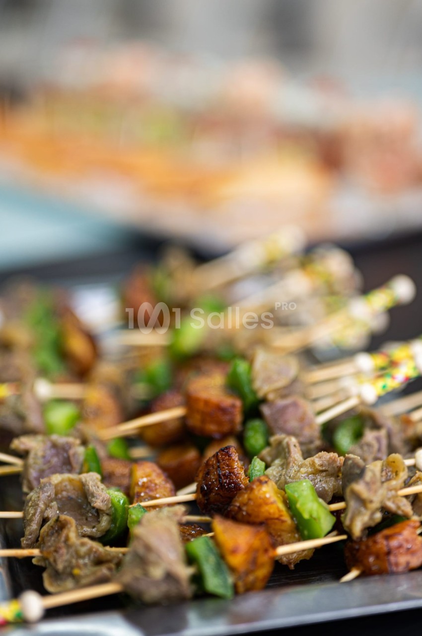 Brochettes de viande grillée avec morceaux de légumes et d'épices, présentées sur un plateau.