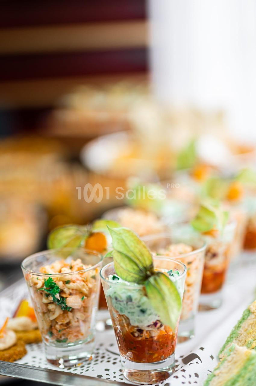 Verrines garnies de crevettes, légumes et herbes fraîches, présentées sur un plateau lors d'un buffet.