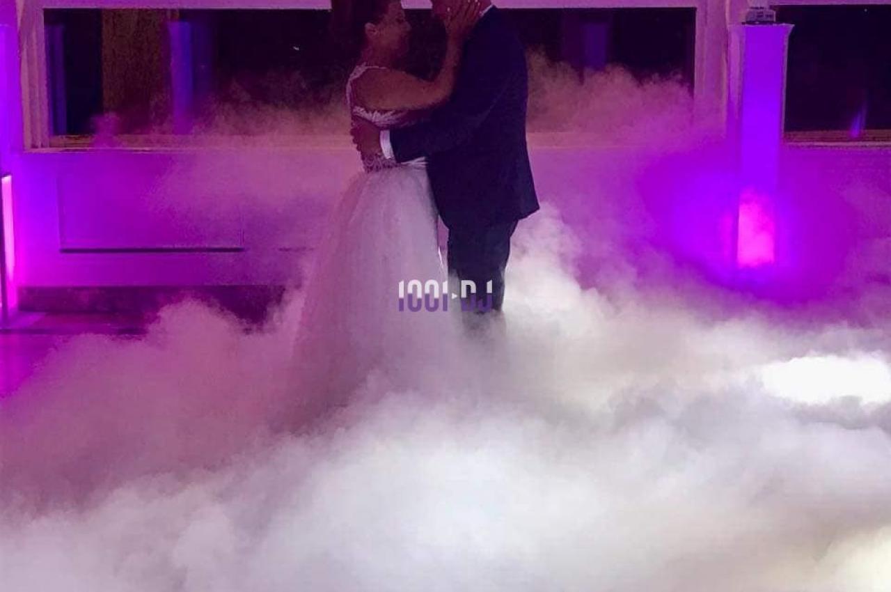 Un couple danse dans une ambiance romantique avec un sol recouvert de fumée et des lumières violettes.