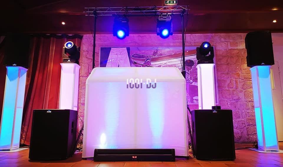 Installation de matériel de sonorisation et éclairage avec une table de DJ illuminée dans une salle en pierre.