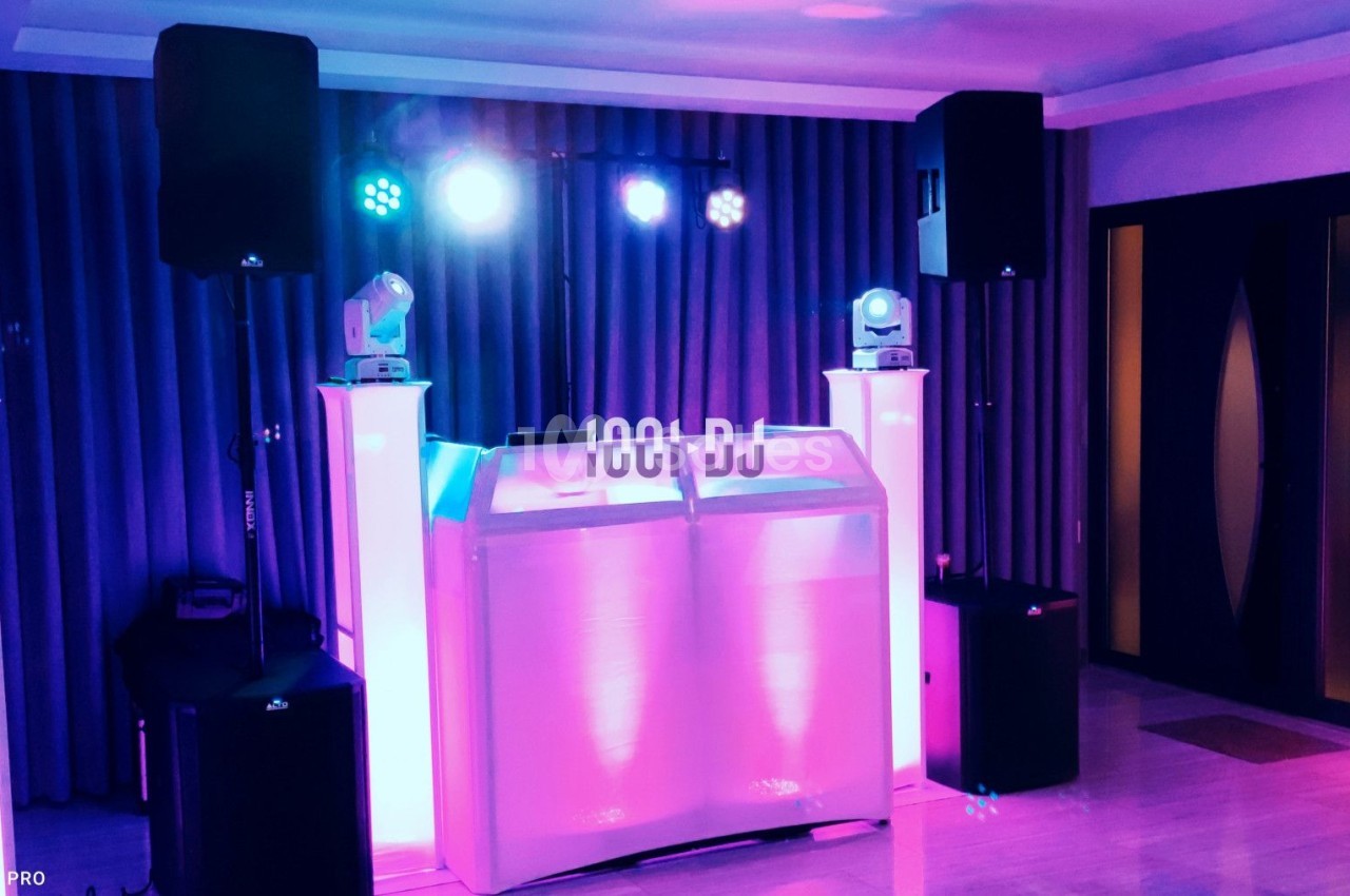 Installation de matériel de sonorisation et éclairage avec une table de DJ dans une salle intérieure.