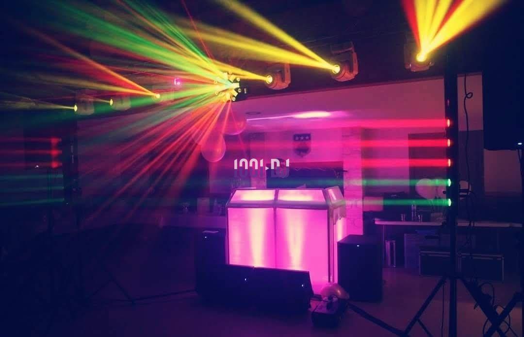 Jeu de lumières colorées projetées autour d'une cabine de DJ dans une salle sombre.