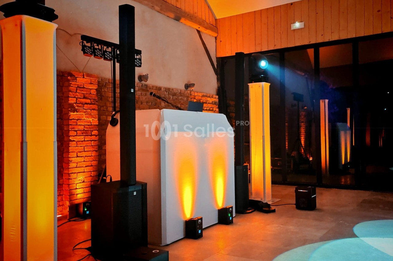 Installation de matériel de sonorisation et d'éclairage dans une salle avec murs en briques et lumière tamisée.