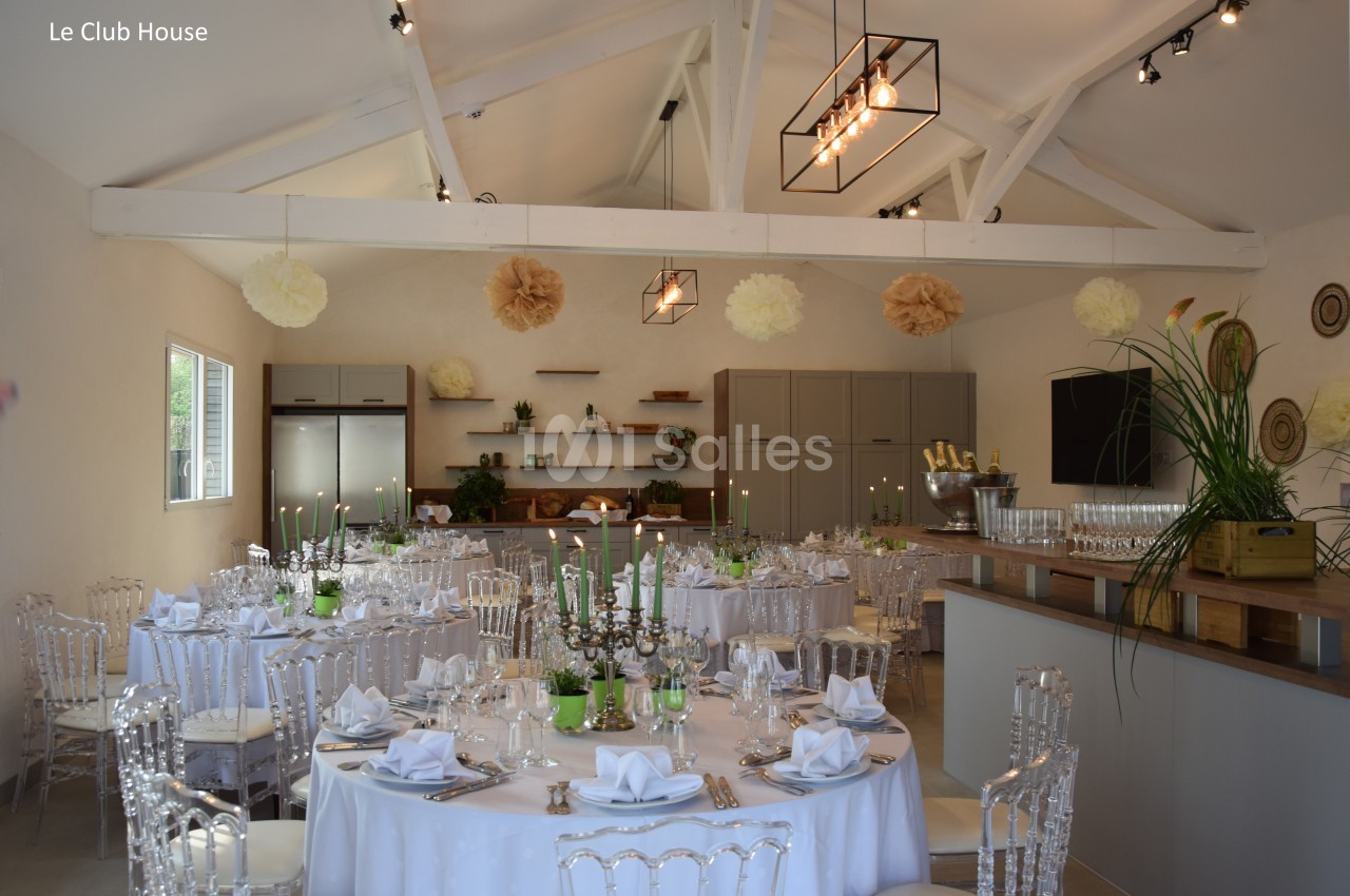 Salle de réception décorée avec des tables rondes dressées, des chandeliers et des éléments suspendus en papier.