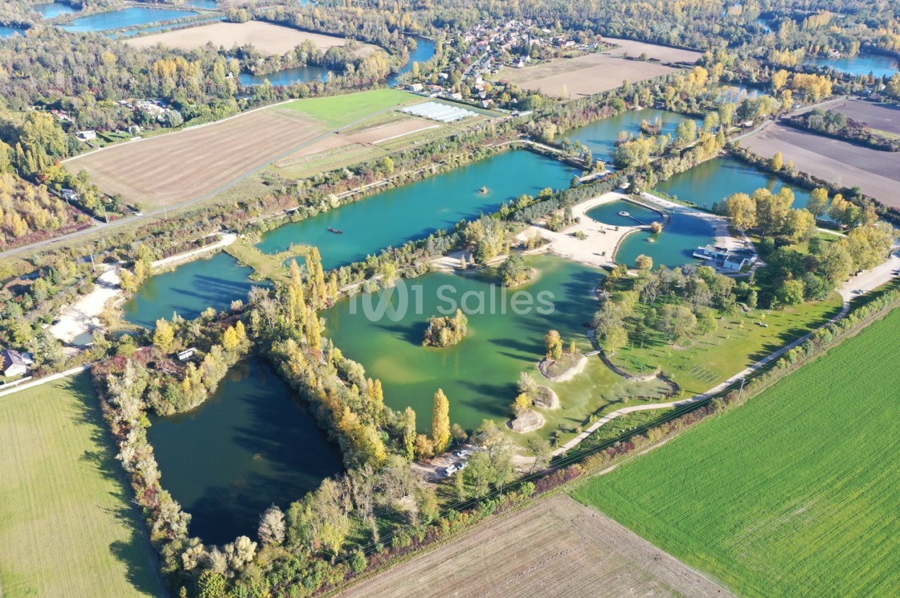 Vue aérienne d'un complexe de lacs entourés de champs, de forêts et de petites infrastructures.