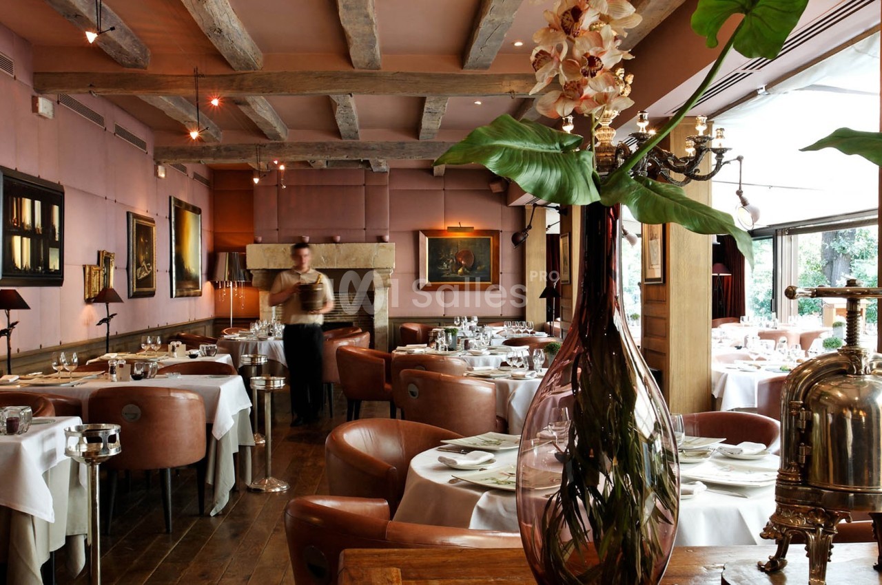 Salle de restaurant élégante avec tables dressées, décoration chaleureuse et un serveur en mouvement.